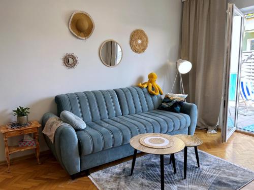 um sofá azul numa sala de estar com uma mesa em Morskie Boho Gdynia Rental em Gdynia