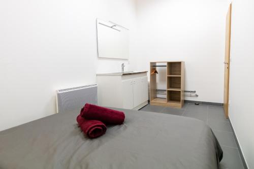 Una toalla roja sobre una cama en LOFT LA MINE D'OR - Parking gratuit et privé - Wifi - Tout équipé - Machine à laver, en Rive-de-Gier