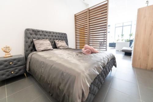 1 dormitorio con 1 cama grande y cabecero gris en LOFT LA MINE D'OR - Parking gratuit et privé - Wifi - Tout équipé - Machine à laver, en Rive-de-Gier
