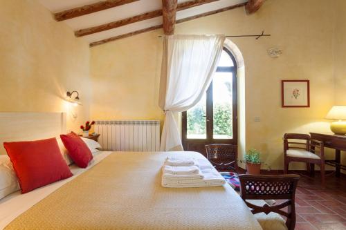 a bedroom with a bed and a table and a window at Agriturismo Bio Aia della Colonna in Saturnia