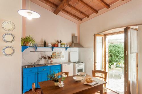 a kitchen with a wooden table and blue cabinets at Agriturismo Bio Aia della Colonna in Saturnia
