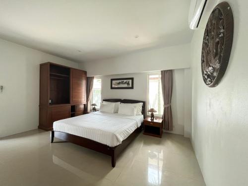 a bedroom with a bed with white sheets and wooden furniture at 拉威查龙山顶大佛三卧泳池别墅Thaiya Villa in Ban Klang
