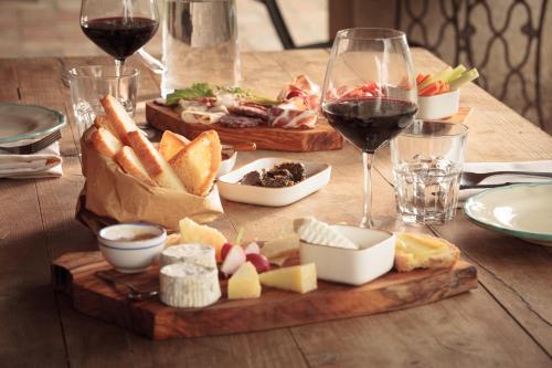 a wooden table with a plate of food and glasses of wine at Agriturismo Bio Aia della Colonna in Saturnia