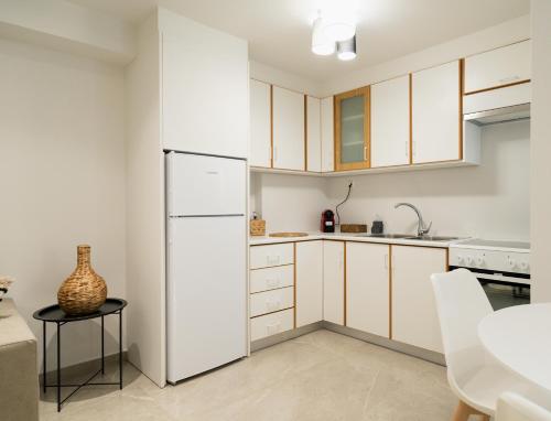 a kitchen with white cabinets and a white refrigerator at Noema Urban Living in Heraklio