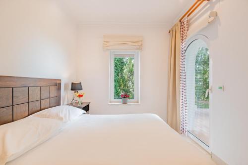 a white bedroom with a large bed and a window at Arcos Gardens Sol Rent Golf in Arcos de la Frontera