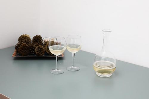 サッサリにあるSogno Allegroの白ワイン三杯と松の円錐のトレイ