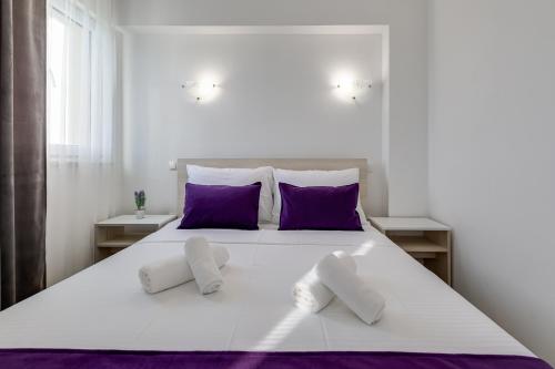 a bedroom with a large white bed with purple pillows at Apartment Miruna s bazenom i jakuzijem in Donje Raštane