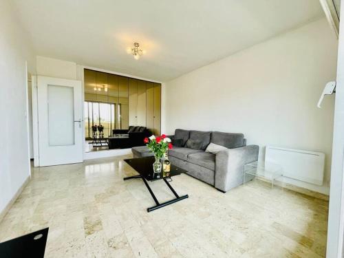 un salon avec un canapé et une table avec des fleurs dans l'établissement Climatisé 2 pièces Vue Mer terasse Parking, à Roquebrune-Cap-Martin