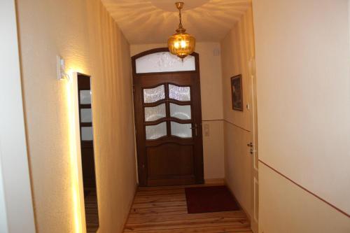 a hallway with a wooden door and a chandelier at Meisenwohnung in Gommern