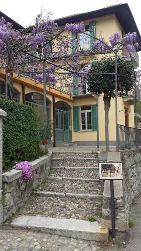 une maison avec des arbres à fleurs violets devant elle dans l'établissement La Séca - Antico Albergo Alzese, à Pella