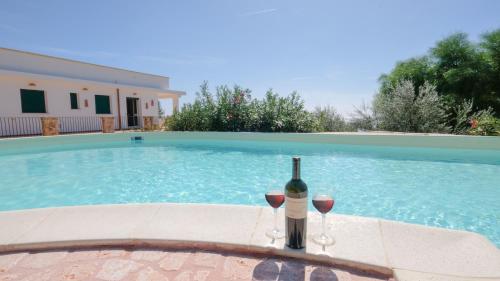 una botella de vino y dos copas junto a la piscina en Villa Opunzie Torre Vado, en Torre Vado