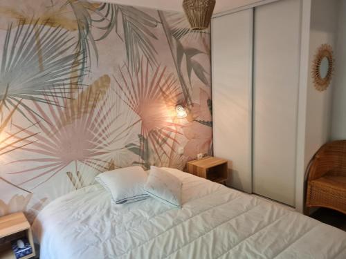 a bedroom with a white bed with a tropical wallpaper at Appartement Rez-de-jardin Terrasse in Aulus-les-Bains