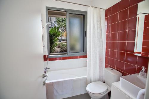 baño con bañera, aseo y ventana en Esprit Villa 21, en Polis Chrysochous