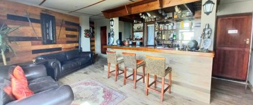 uma sala de estar com um bar com um sofá e cadeiras em Revive Guesthouse em Darling