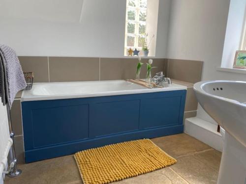 uma casa de banho com uma banheira azul e um lavatório. em Character Snowshill Cottage - 2 Glebe Cottage’s em Snowshill