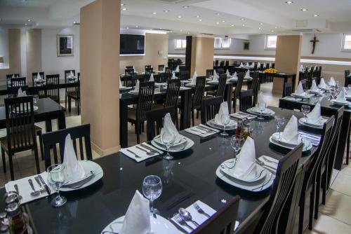 uma sala de jantar com mesas pretas e cadeiras com guardanapos em Hotel Lux em Medjugorje