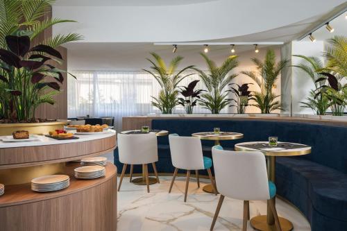 里米尼的住宿－Parioli Hotel Rimini，一间设有桌椅的餐厅,种植了棕榈树