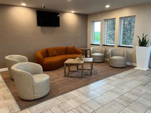 a waiting room with a couch and chairs and a tv at Orangewood Inn & Suites Kansas City Airport in Kansas City