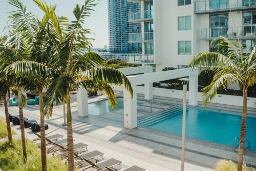 a view of the pool from the balcony of a building with palm trees at Luxury Oceanview Studio at Miami Design District in Miami