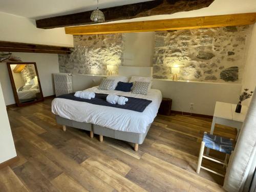 een slaapkamer met een bed en een stenen muur bij Le Val Éveillé 4 étoiles - maison de maître de 1773 in Arudy