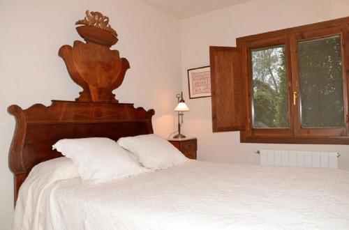 ペラタリャーダにあるCan Coll Peratalladaのベッドルーム1室(木製ヘッドボードと窓付)