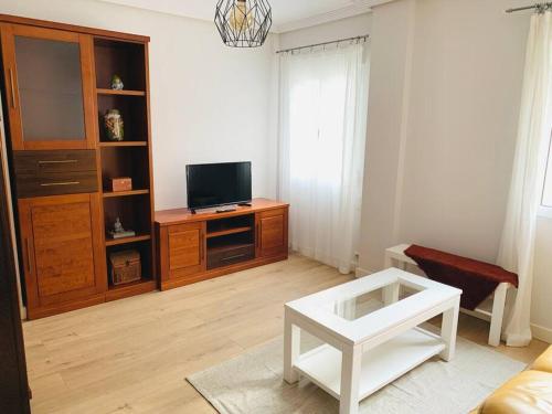 a living room with a tv and a white table at Apartamento Ruiz Zorrilla in Santander