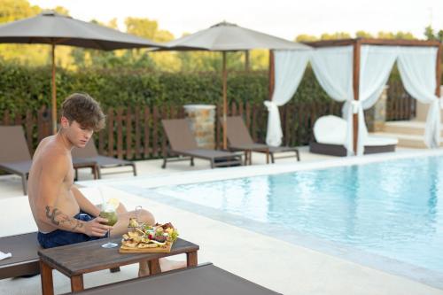 un hombre sentado junto a una piscina con una bandeja de comida en Country House L'Aia - Wellness & Relax, en Casal Velino