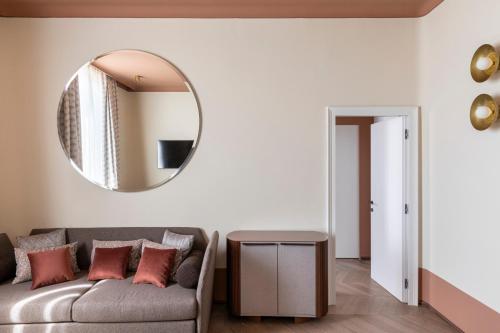 a living room with a couch and a mirror at Palazzo Velabro, a Member of Design Hotels in Rome