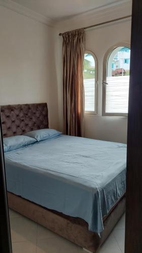 een bed in een slaapkamer met 2 ramen bij Appartement résidence lilia al jabal M'diq in M'diq