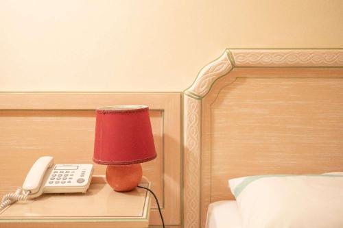 a red lamp and a phone on a table next to a bed at Hotel Royal Terme in Ischia