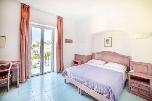 Un dormitorio con una cama y una ventana grande. en Hotel Royal Terme, en Isquia