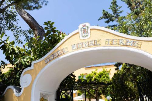 an archway in front of a yellow building with trees at Hotel Royal Terme in Ischia