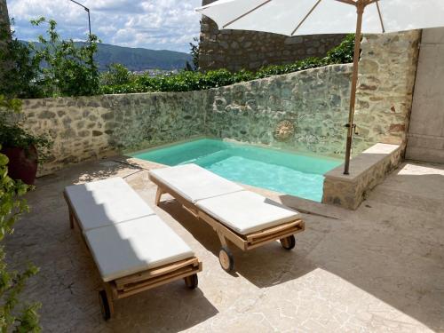 einen Pool mit 2 Stühlen und einem Sonnenschirm in der Unterkunft Les Vieux Murs in Montfort