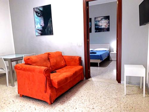レッチェにあるAppartamenti Raffaelloの鏡付きのリビングルームにオレンジのソファ