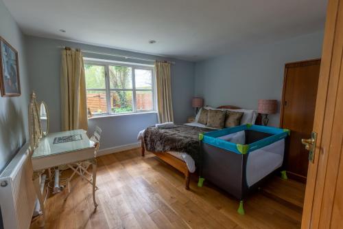 um quarto com uma cama, uma secretária e uma janela em Modernised seven bedroom country house and garden with hot tub em Cranbrook