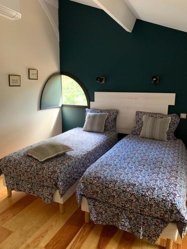 2 Betten in einem Zimmer mit grünen Wänden in der Unterkunft Gîtes de Charme "LE BIBENDÔME" et "LES MOTS BLEUS en pleine forêt in Cause-de-Clérans