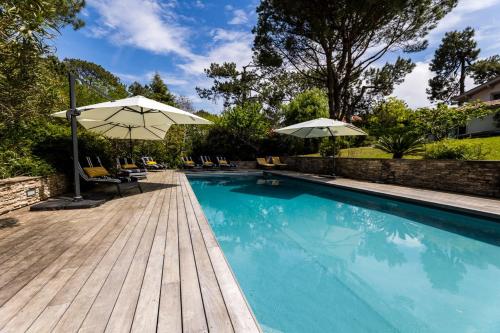 - une piscine avec des parasols et des chaises à côté d'une terrasse en bois dans l'établissement SERENITY - KEYWEEK Bidart swimming pool villa, à Bidart