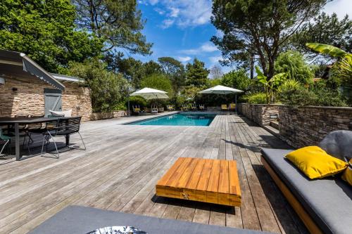 une arrière-cour avec une piscine et une terrasse en bois avec une table dans l'établissement SERENITY - KEYWEEK Bidart swimming pool villa, à Bidart