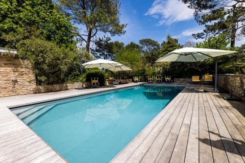 - une piscine avec parasols sur une terrasse en bois dans l'établissement SERENITY - KEYWEEK Bidart swimming pool villa, à Bidart