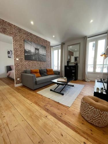 un salon avec un canapé et un mur de briques dans l'établissement Le New York Appart' T1 Bis au centre du MANS, au Mans