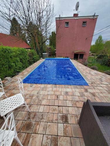 una piscina con 2 sillas y una casa en Kenese Apartman en Balatonkenese