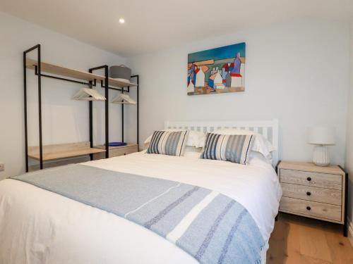 a bedroom with a large white bed and a night stand at Beach Cottage in Helston
