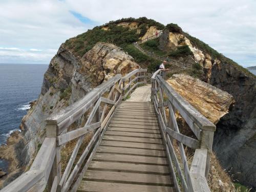 a person walking down a wooden staircase on a cliff at Paraíso Ortegal in Feás