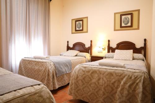 ein Hotelzimmer mit zwei Betten und einem Fenster in der Unterkunft Hostal Rocio in Sanlúcar la Mayor