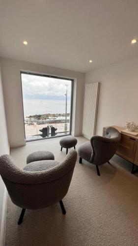 a living room with two chairs and a large window at Morelli Plaza Portstewart in Portstewart
