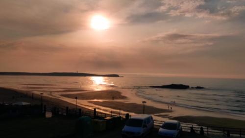 a sunset over a beach with cars parked at Paraíso Ortegal in Feás