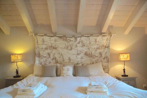 a white bed with two towels on top of it at Chalet à Crans-Montana 17 personnes in Crans-Montana