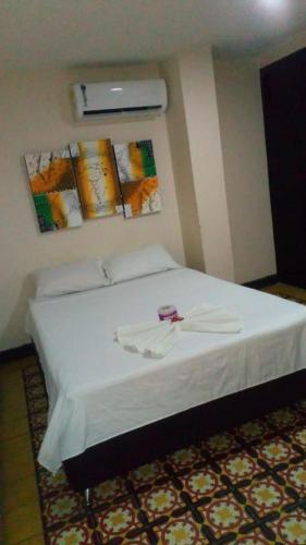 a bedroom with a bed with a white bedspread and avisor at EL Dorado Hotel Maicao in Maicao