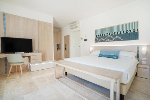 a bedroom with a bed and a desk and a tv at La Coluccia in Santa Teresa Gallura