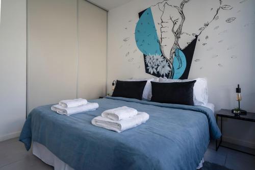 Un dormitorio con una cama azul con toallas. en Fliphaus Malabia 1900 - Loft Plaza Armenia en Buenos Aires